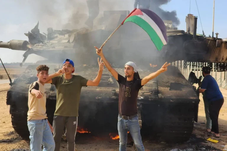 O braço armado do Hamas, as Brigadas Izz ad-Din al-Qassam, seguram uma bandeira palestina enquanto destroem um tanque das forças israelenses na Cidade de Gaza, Gaza, em 7 de outubro de 2023 [Hani Alshaer – Agência Anadolu]