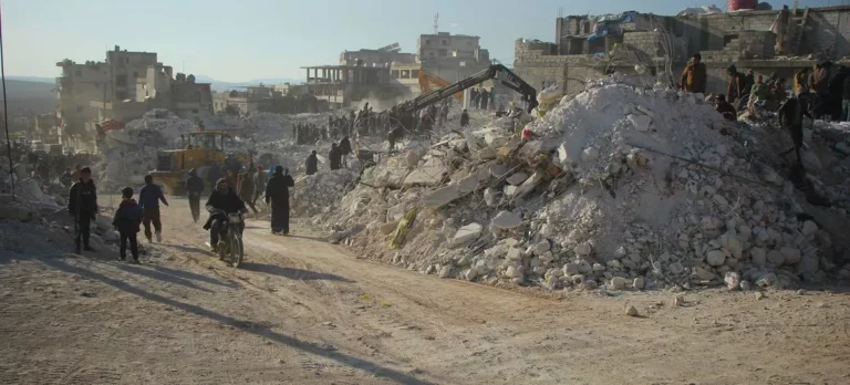 Moradores passam pelos escombros de edifícios desabados em Harém, na Síria, após o terremoto de fevereiro de 2023 [ PMA ]