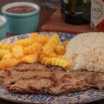 Contra filé metido a picanha 2.0 A versão 2.0 do contra filé conta com 200g de carne e continua sendo puro sabor! É servido ao ponto da casa (mal passado) e acompanha, farofinha, arroz e molho à campanha. O cliente pode escolher a famosa batata morna ou porção de fritas