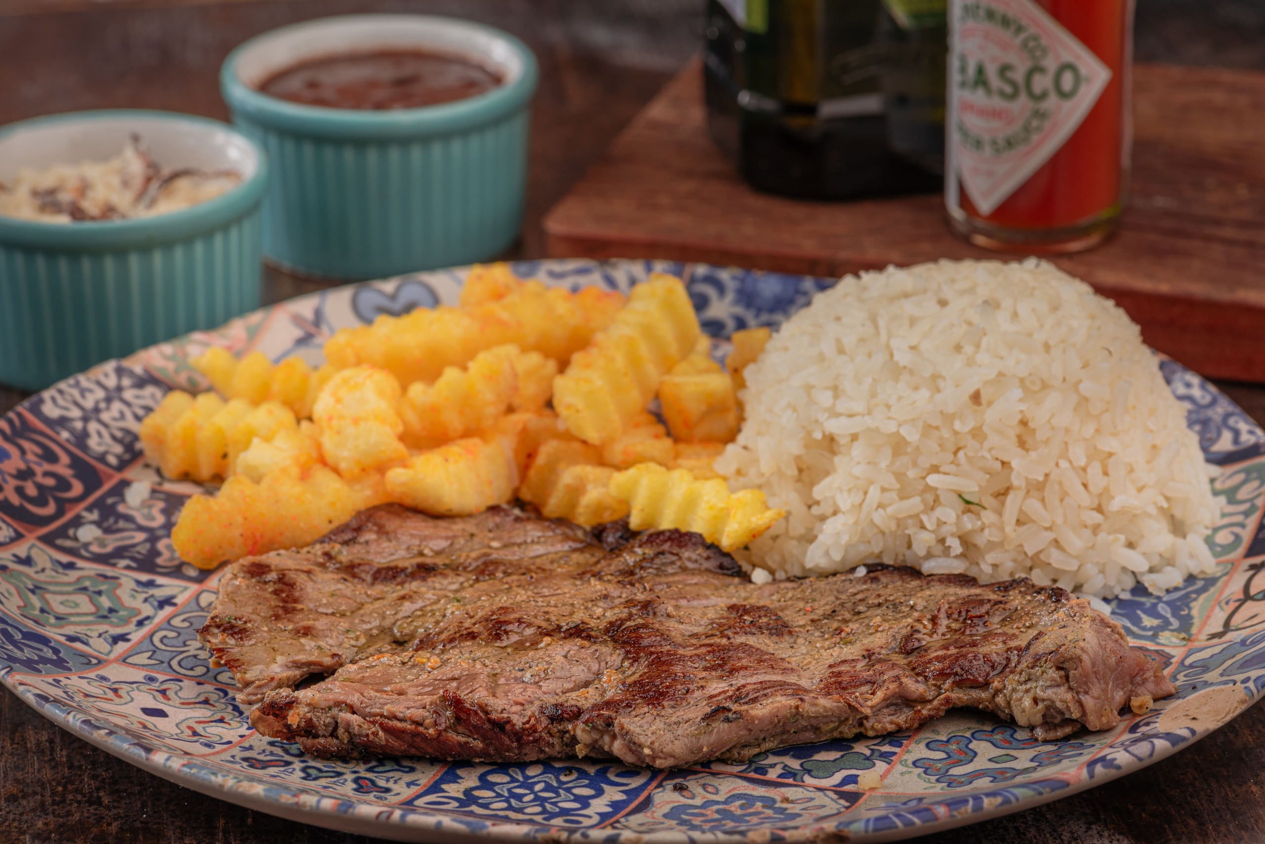 Contra filé metido a picanha 2.0 A versão 2.0 do contra filé conta com 200g de carne e continua sendo puro sabor! É servido ao ponto da casa (mal passado) e acompanha, farofinha, arroz e molho à campanha. O cliente pode escolher a famosa batata morna ou porção de fritas