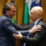 Bolsonaro (à esquerda) e Moraes se cumprimentam durante cerimônia de posse do ministro na presidência do TSE em 2022 - SERGIO LIMA / AFP