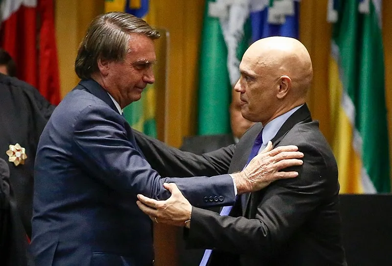 Bolsonaro (à esquerda) e Moraes se cumprimentam durante cerimônia de posse do ministro na presidência do TSE em 2022 - SERGIO LIMA / AFP