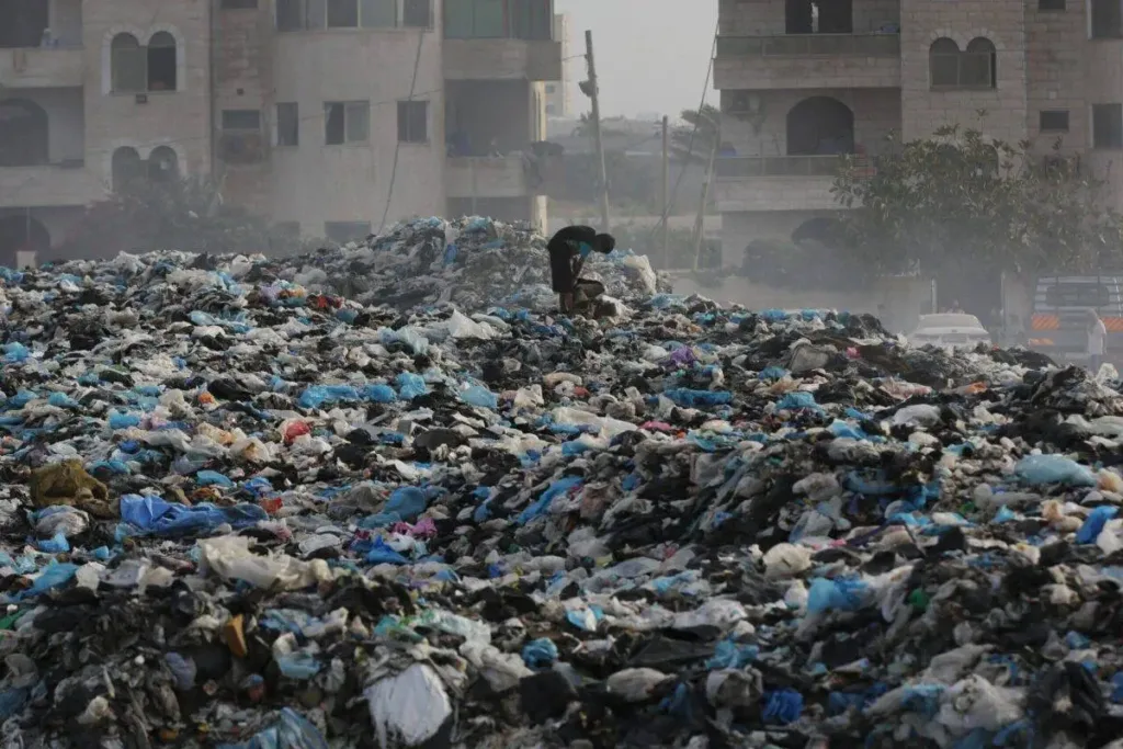 Criança vasculha uma pilha de lixo diante da crise de fome que assola Gaza, sob cerco de Israel, em Deir al Balah, 26 de maio de 2024 [Ashraf Amra/Agência Anadolu]
