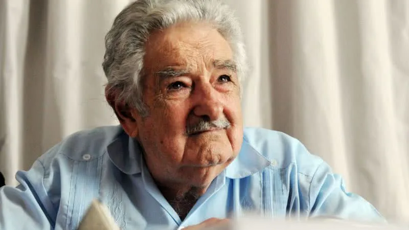 Pepe Mujica na frente de cortinas brancas