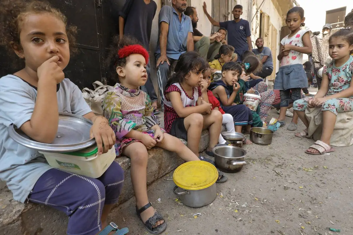 Palestinos, que se refugiaram no campo de refugiados de Nuseirat devido aos ataques israelenses, esperam na fila para receber alimentos, distribuídos por uma organização de caridade na Cidade de Gaza, Gaza, em 18 de outubro de 2024. [Moiz Salhi – Agência Anadolu]