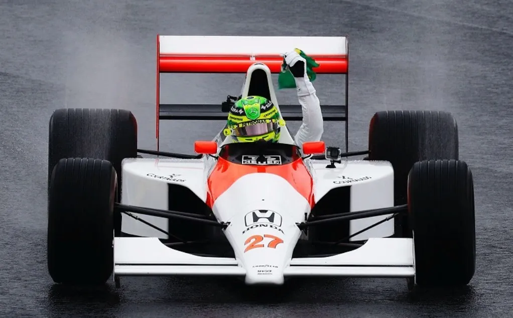 Hamilton homenageia Senna com McLaren MP4/5B em Interlagos, levanta bandeira do Brasil e emociona público sob forte chuva.