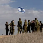 Soldados de Israel hasteiam bandeira perto da fronteira com Gaza, em 5 de dezembro de 2024 [Amir Levy/Getty Images]